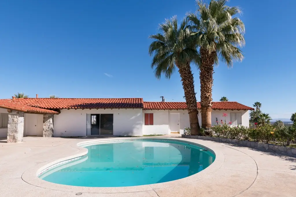 Single-story home with a pool and tall palm trees